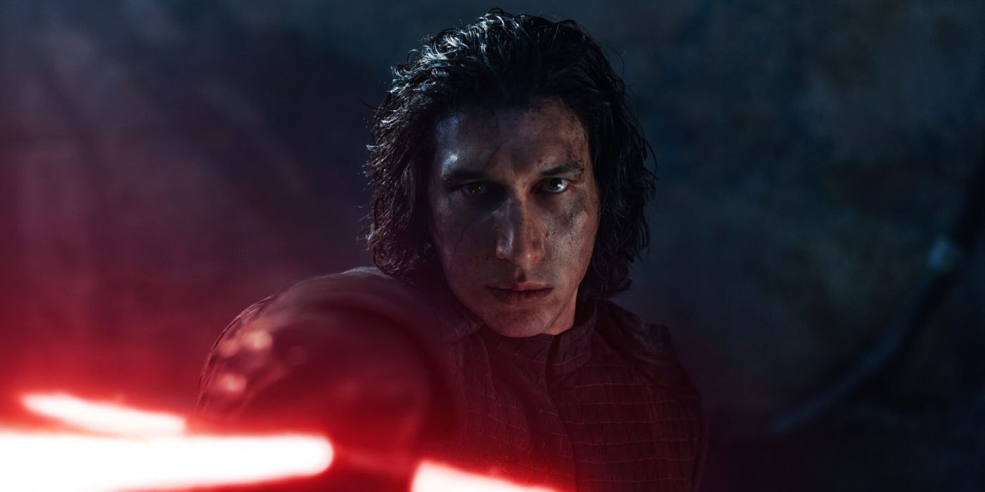 Kylo Ren/Ben Solo (Adam Driver) holds up his red lightsaber, glaring down the hilt 