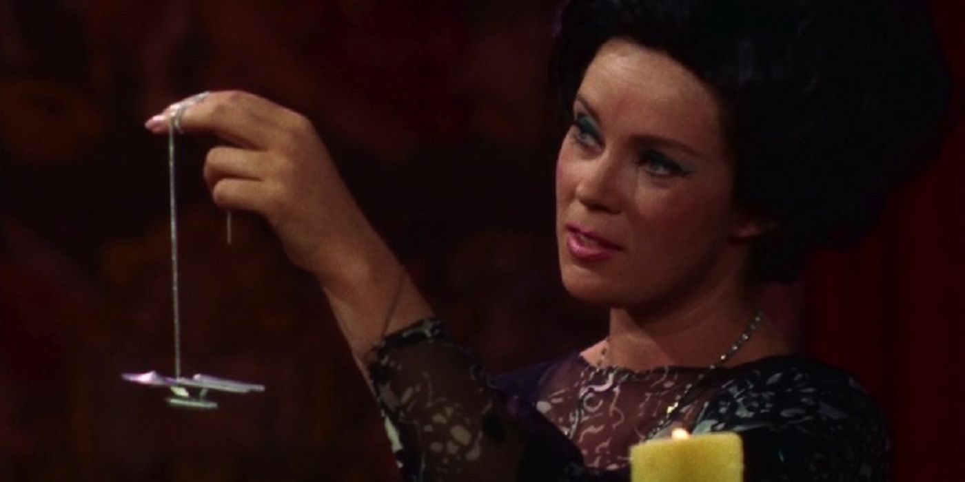 In Star Trek, a woman sits by a candle and holds up a chain with a miniature version of the Enterprise on the end.