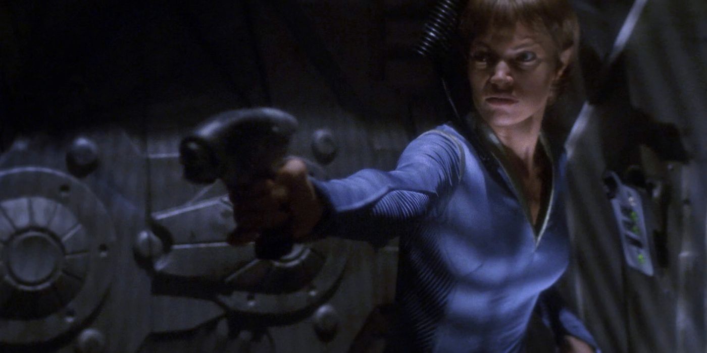 In Star Trek: Enterprise, a crew member points a weapon in a dark hallway and appears frightened.