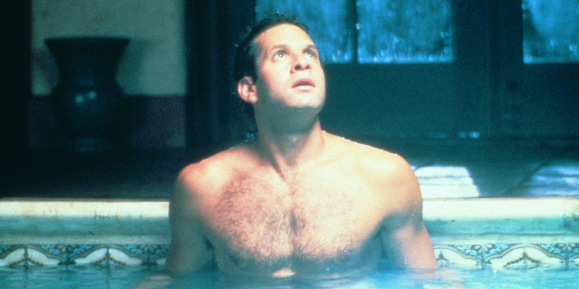 Steve Guttenberg wearing a bathing suit in a pool, looks up toward a bright beam of light in Cocoon, 1985.
