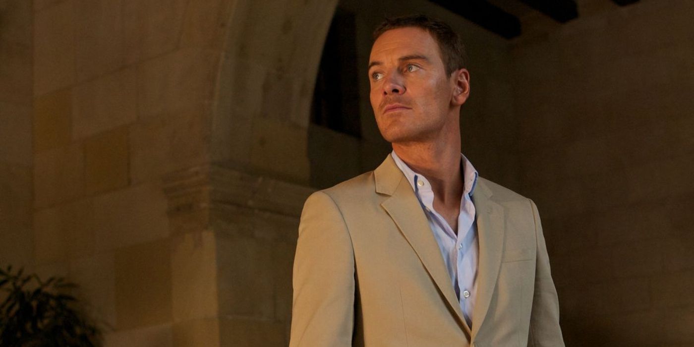 Michael Fassbender wears a tan suit and sunglasses as he looks around the interior of a grand brick building in 'The Counselor' (2013).