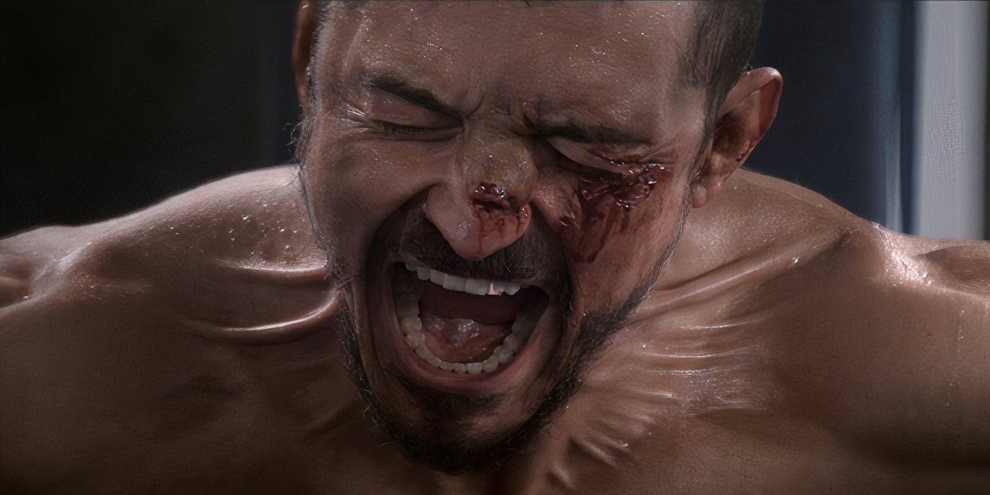 A still of a shirtless man screaming with bleeding cuts on his face