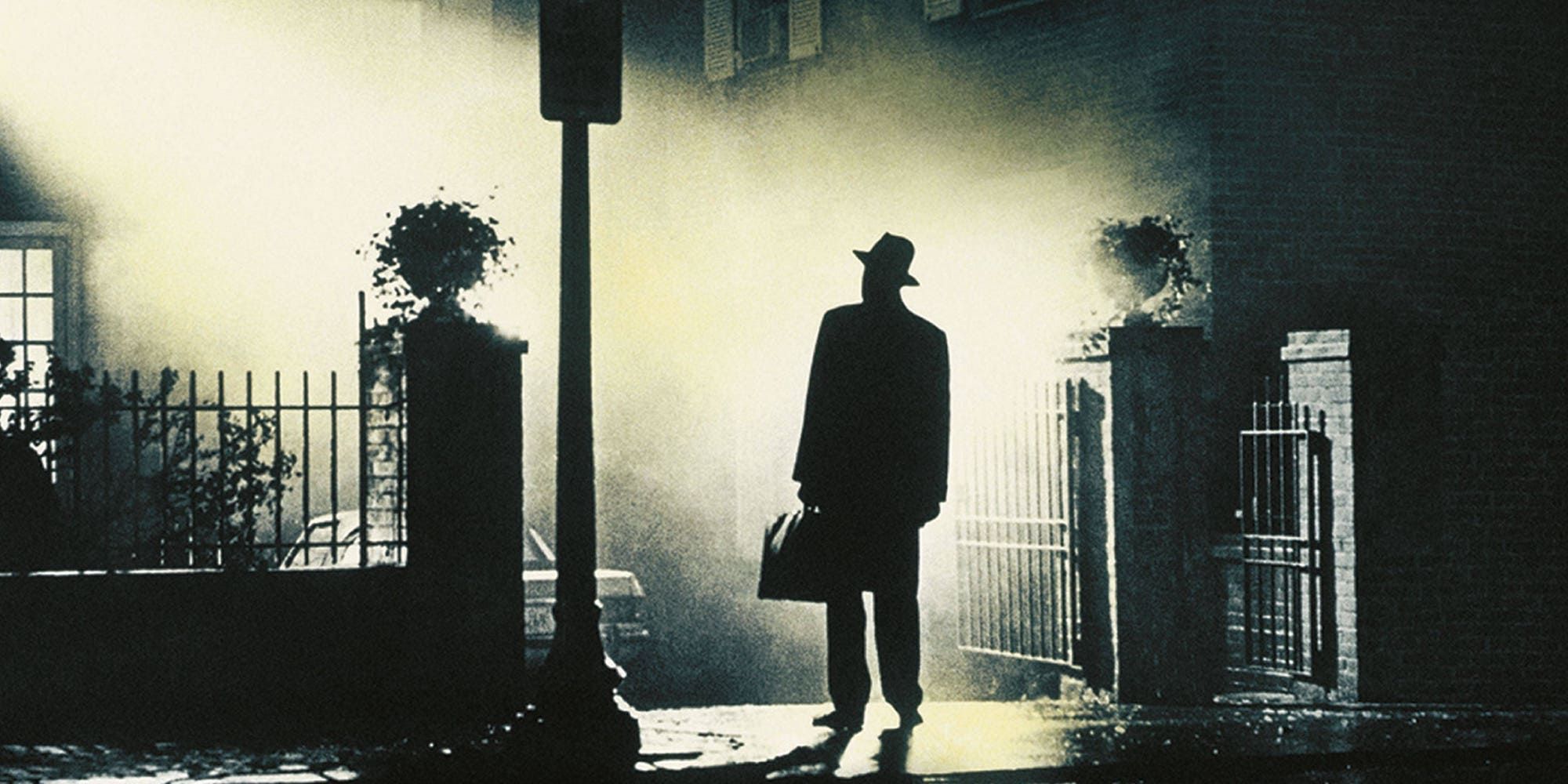 A priest standing outside a house at night in The-Exorcist 