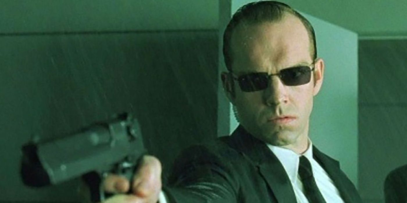 Agent Smith (Hugo Weaving) in a room aiming a pistol as water sprays everywhere in 'The Matrix' (1999).
