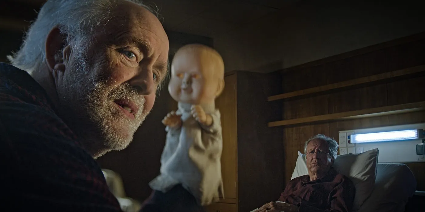 John Lithgow holding up a doll while Geoffrey Rush looks up from bed in The Rule of Jenny Pen