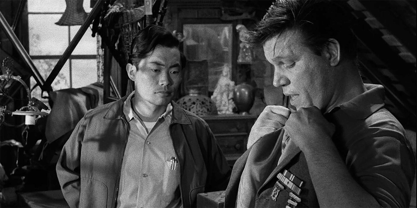 George Takei looking at Neville Brand, holding up a uniform, in a black and white picture for The Twilight Zone