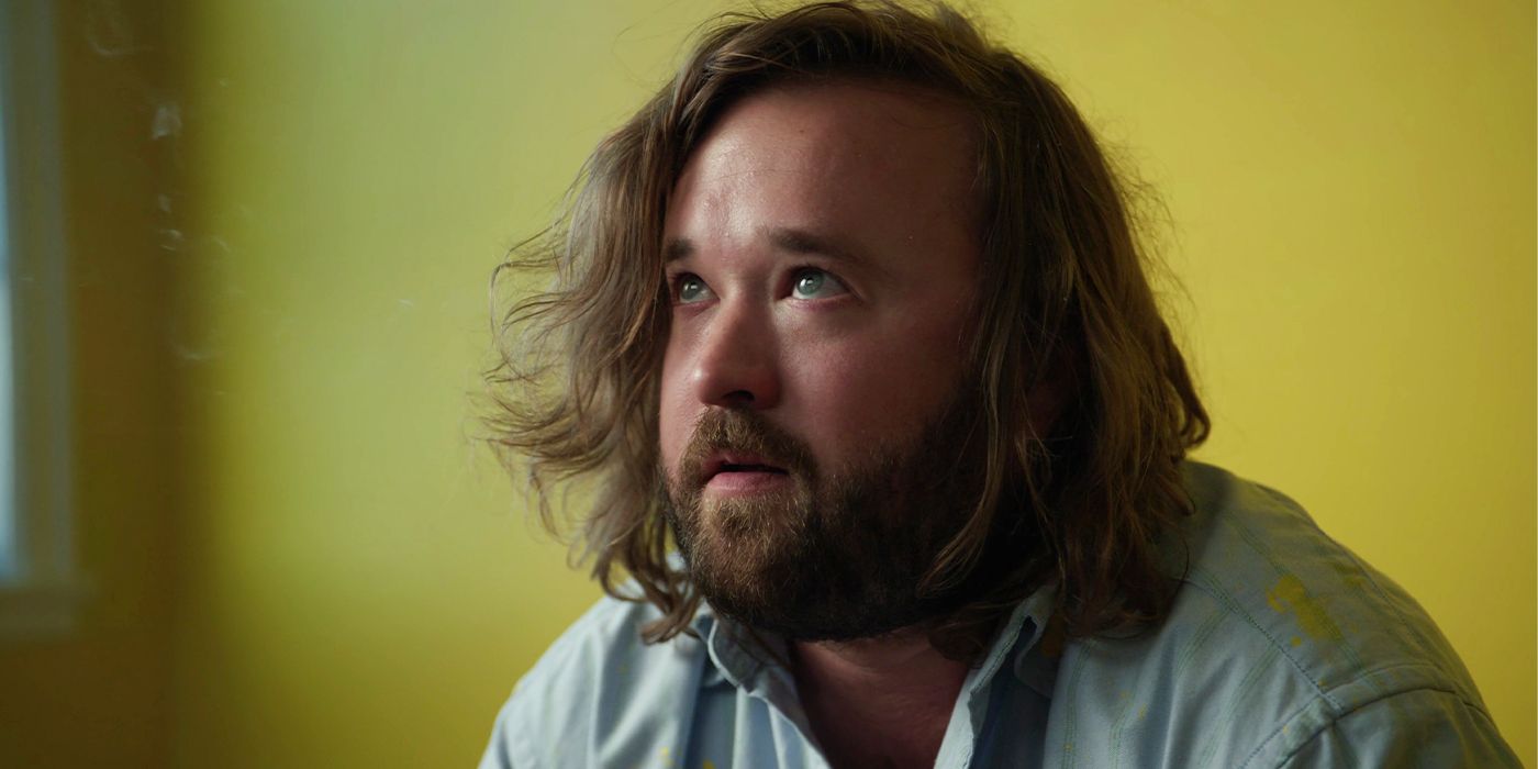 Haley Joel Osment on the ground in front of a yellow wall looking up 