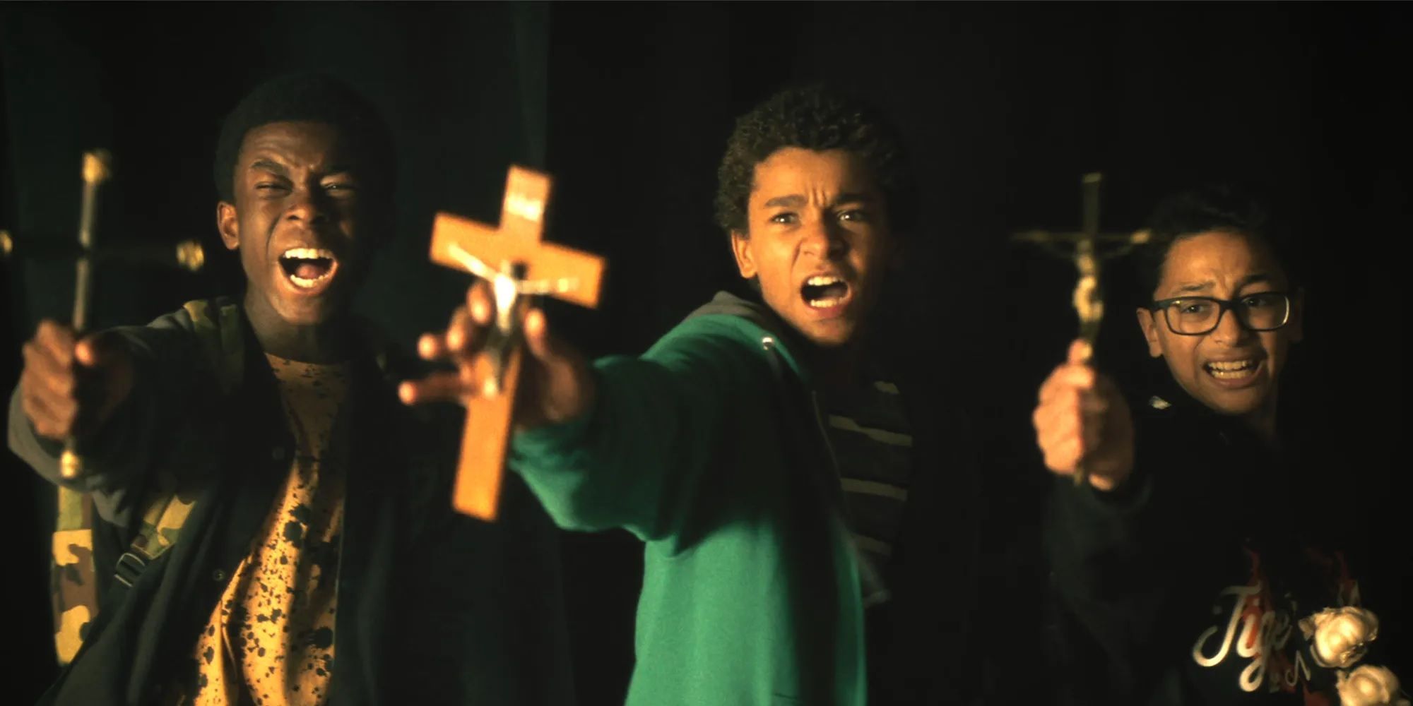 Three teenagers hold up crosses and look afraid in Vampires vs. the Bronx.