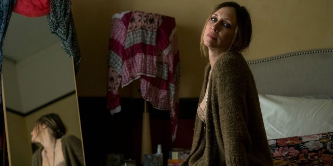 Vera Farmiga sentada en una cama y mirando a cámara en 