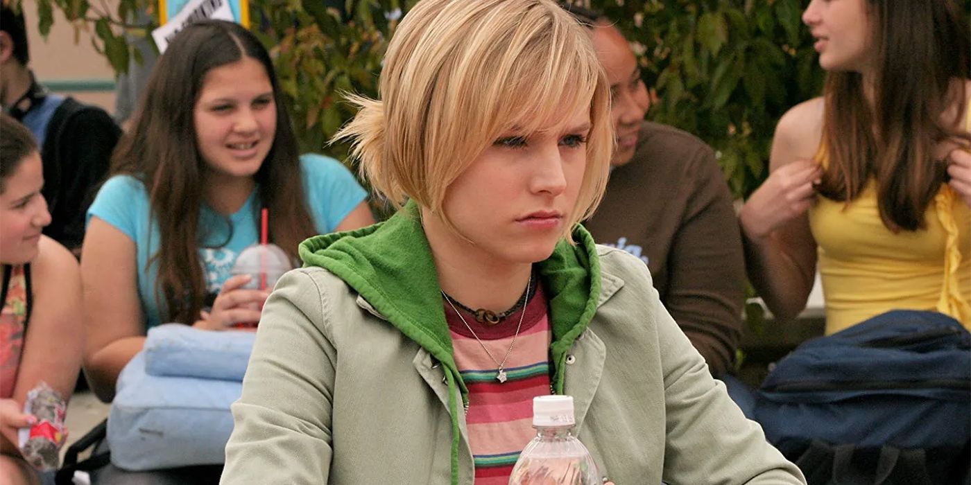 Kristen Bell sitting at a lunch table and looking in the distance in Veronica Mars.