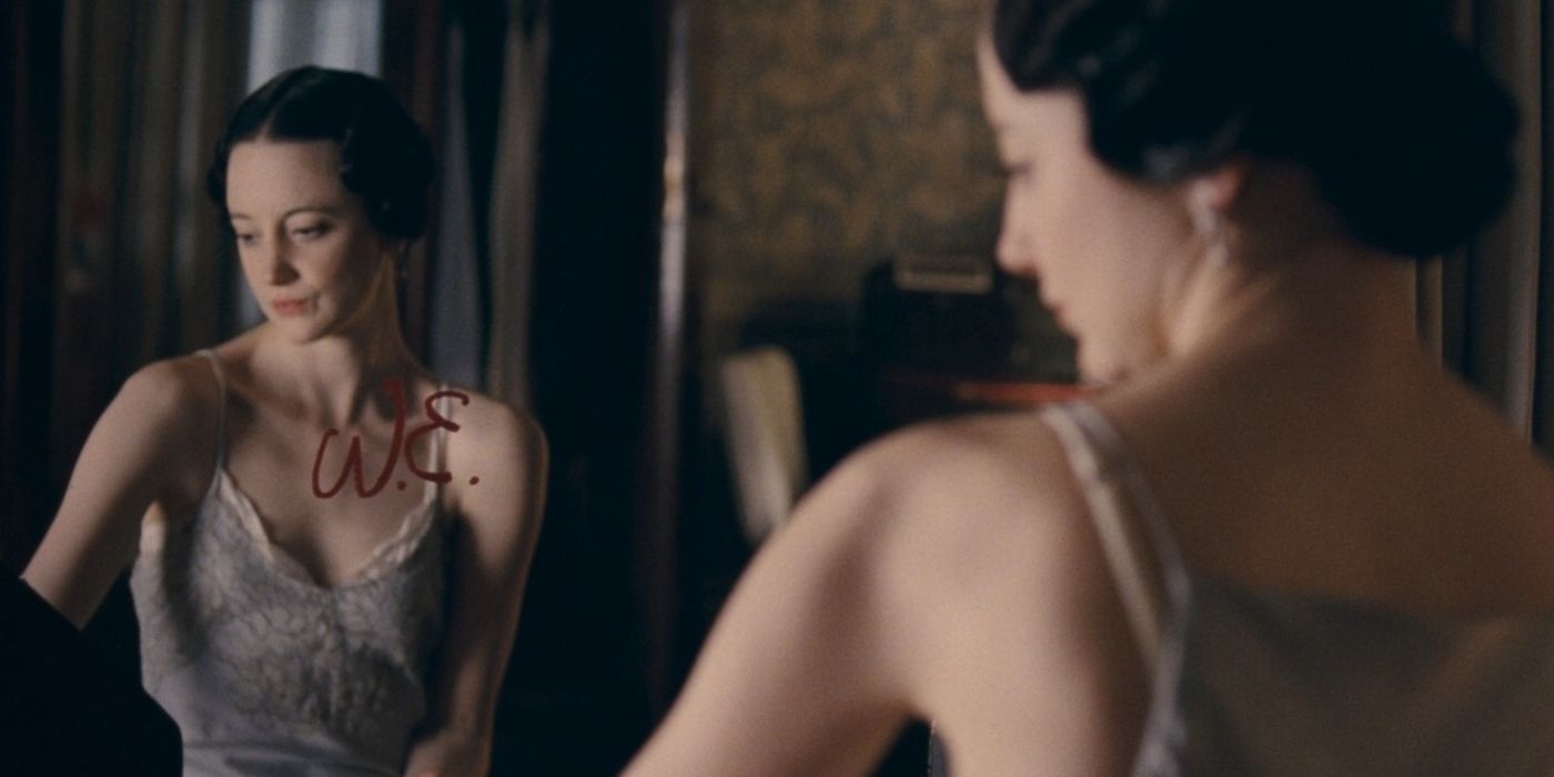 Wallis wears a nightdress as she looks in a mirror with "W.E." written on it.