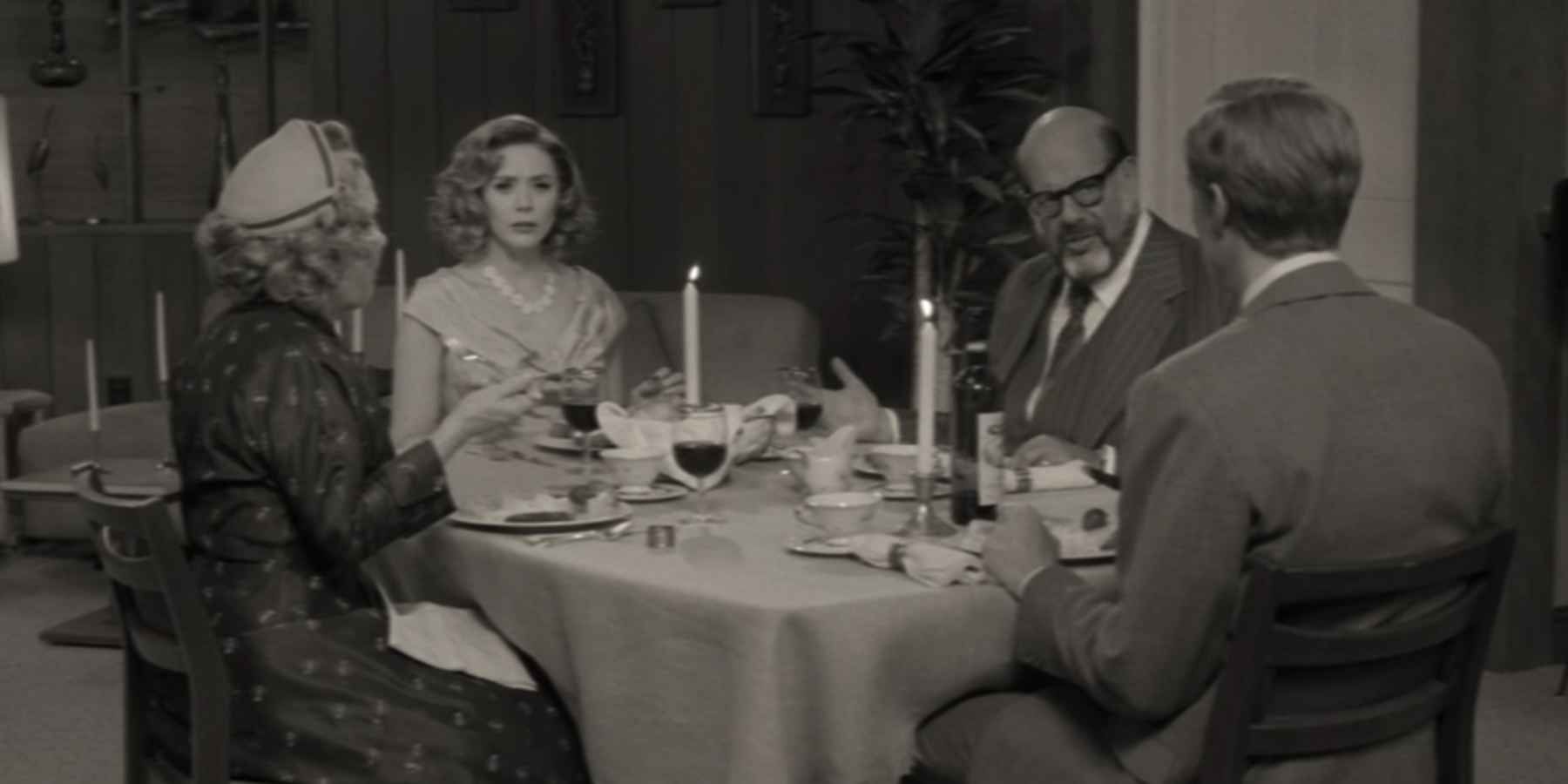 Mr. & Mrs. Hart, Wanda, and Vision seated at a dining table in a black and white episode of 'WandaVision'