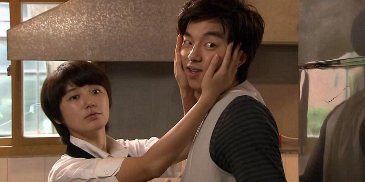 One person has their hands on the other's face and turns their gaze to look off camera in Coffee Prince.