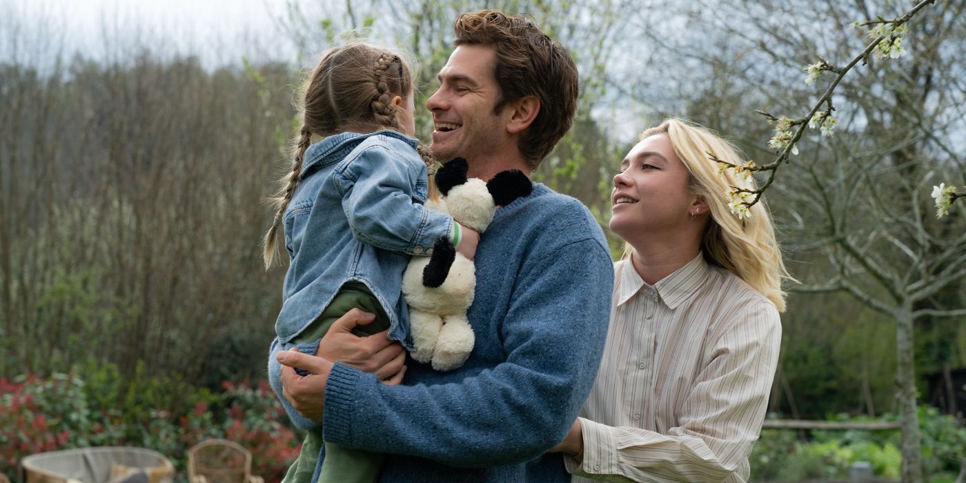 Andrew Garfield y Florence Pugh sonríen mientras cargan a una niña en Vivimos en el tiempo.