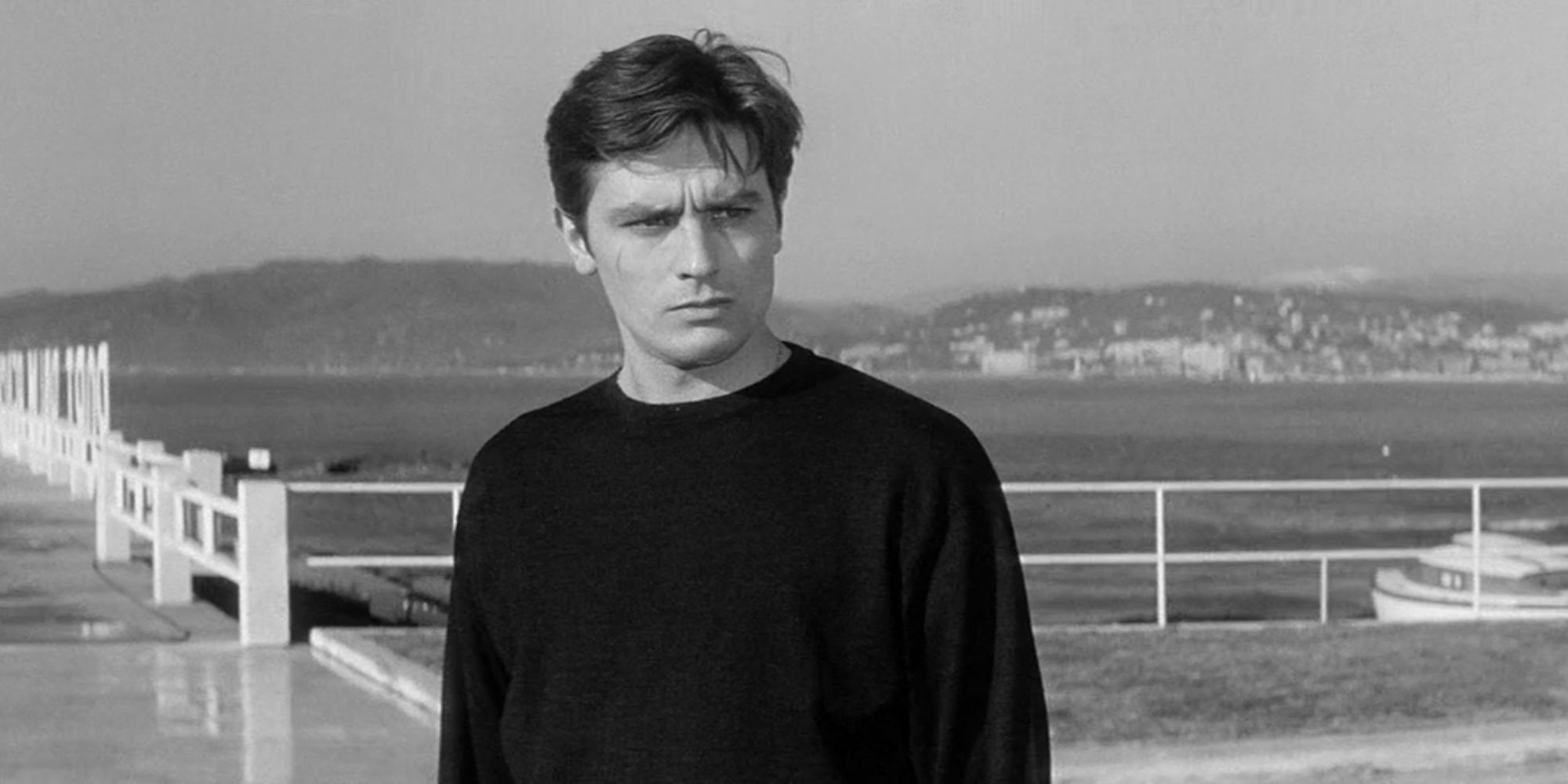 Alain Delon stands on a boat dock looking serious in Any Number Can Win (1963).