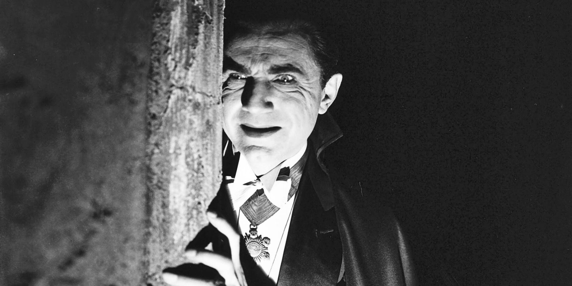 Bela Lugosi as Count Dracula peering out behind a wall in Dracula (1931)