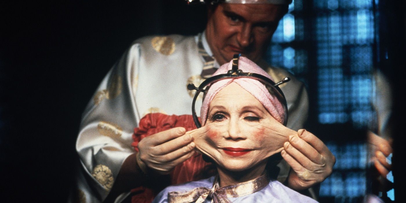 A woman in a chair with a head brace on has the skin of her face stretched by a man standing behind her in Brazil.