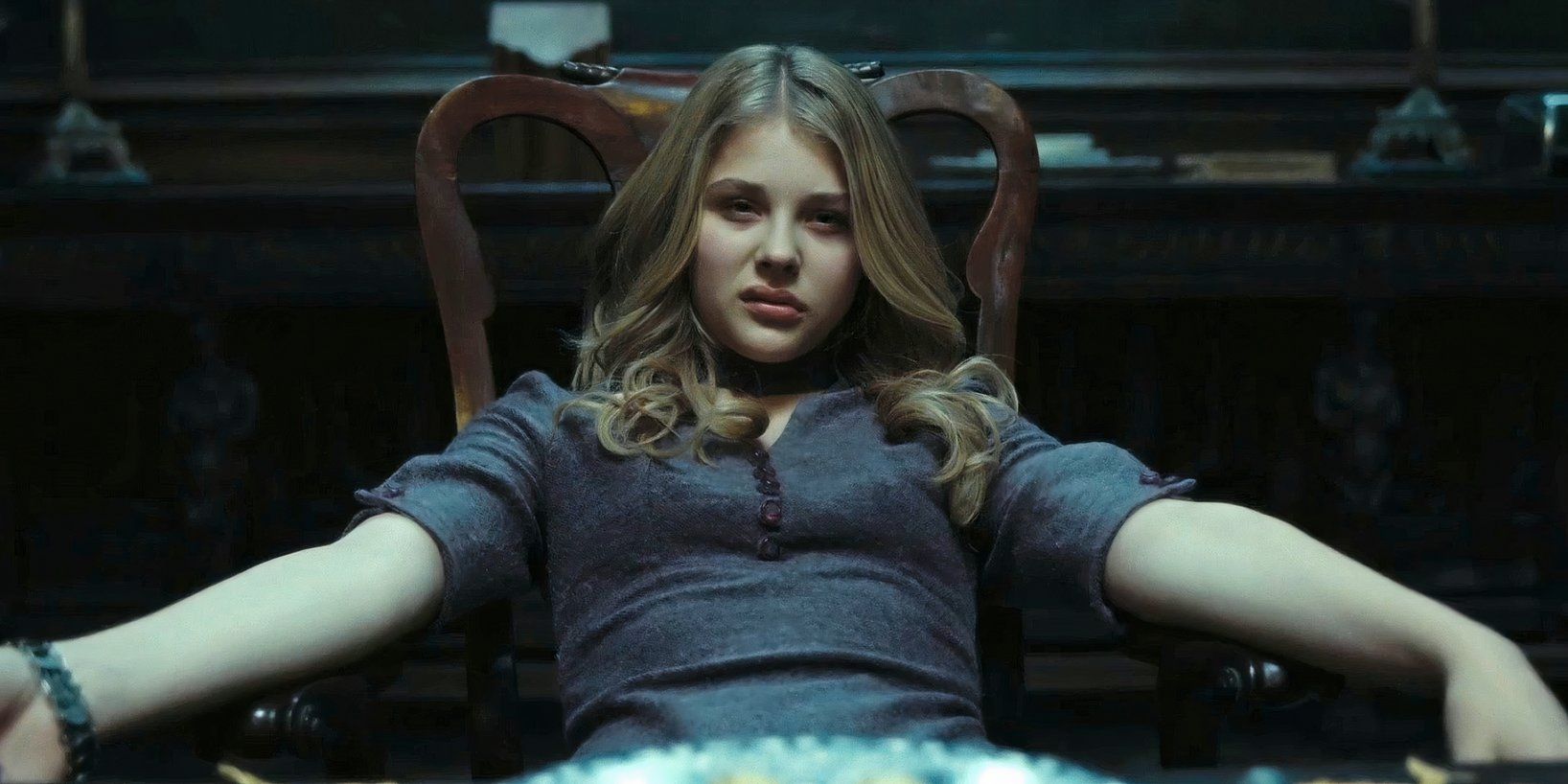 Chloë Grace Moretz as Carolyn Stoddard sits in a chair looking bored and annoyed in Dark Shadows.