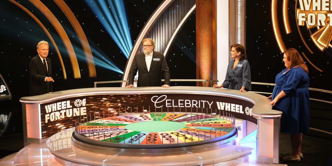 Pat Sajak & contestants stand near a large wheel with dollar amounts on it in Celebrity Wheel of Fortune.