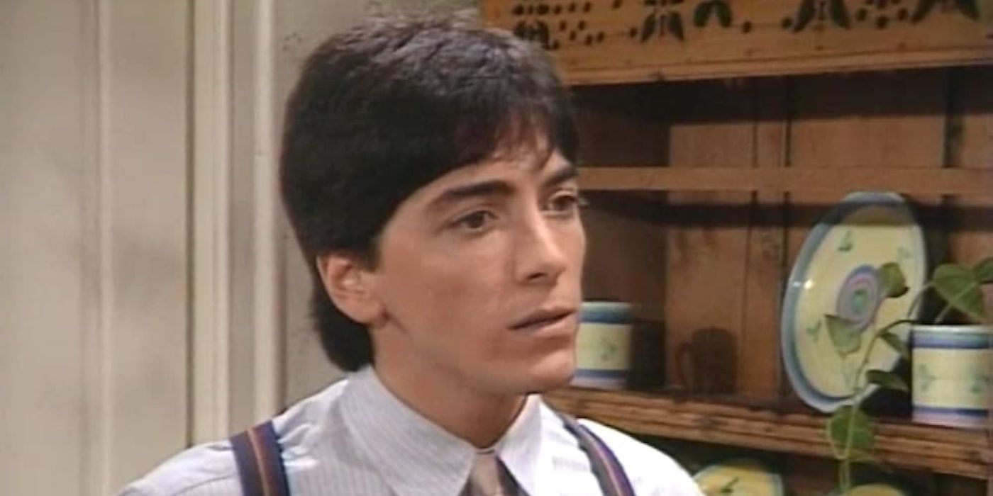 Scott Baio as Charles stands in front of shelves and looks serious in Charles in Charge.