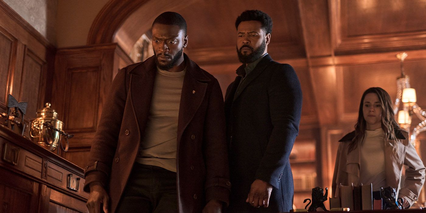 Aldis Hodge as Cross and Isaiah Mustafa as Sampson looking down at something in shock in a wood-paneled room