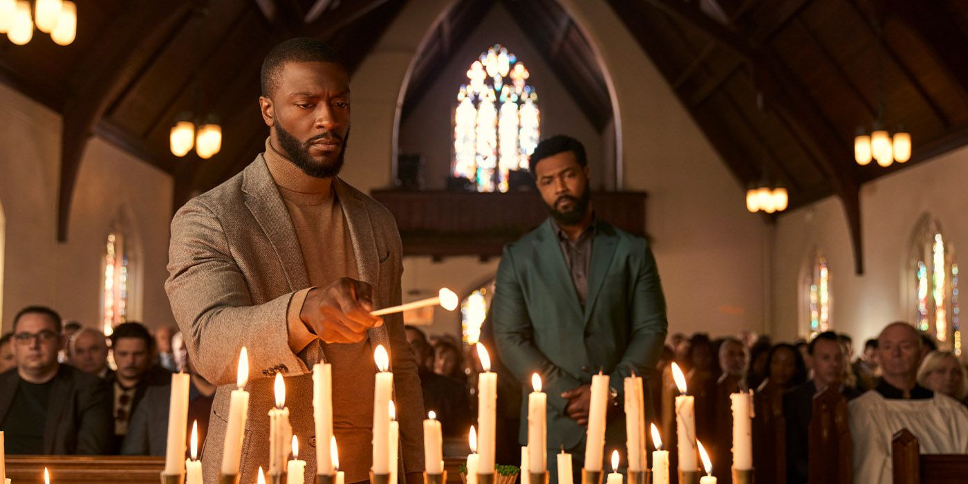Aldis Hodge as Alex Cross lighting a candle in a church with Isaiah Mustafa as Sampson watching from behind