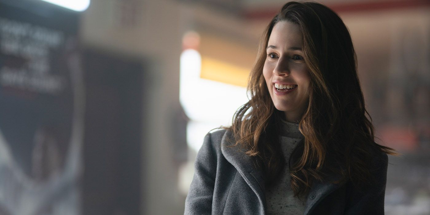 Alona Tal as Kayla in a coat smiling at someone off-screen in Cross