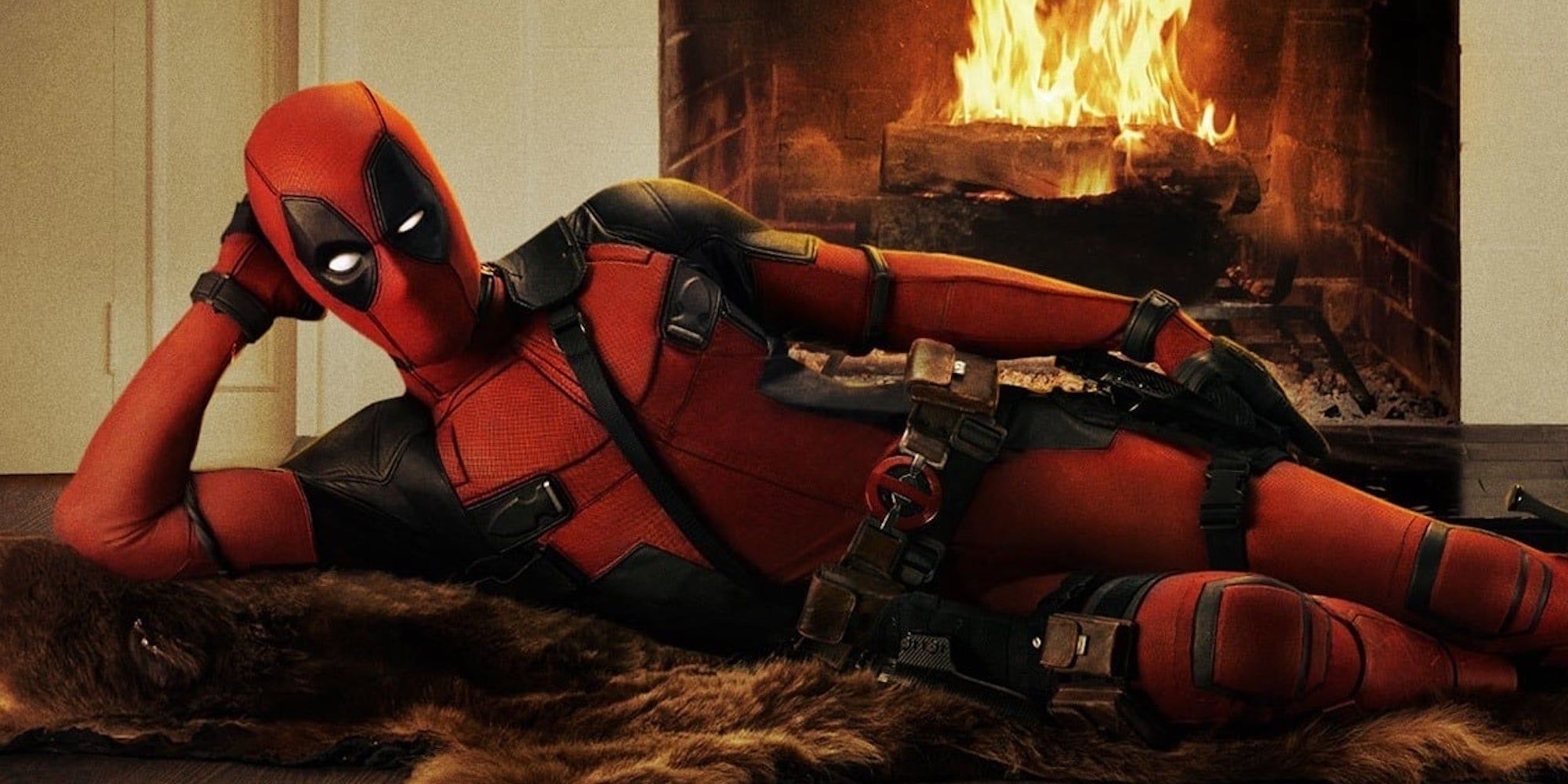 Deadpool laying on a carpet with a fireplace behind.