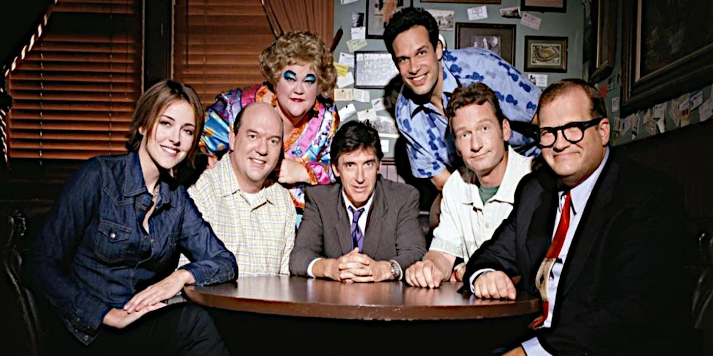 The cast of the Drew Carey Show poses for a promotional photo in a bar.