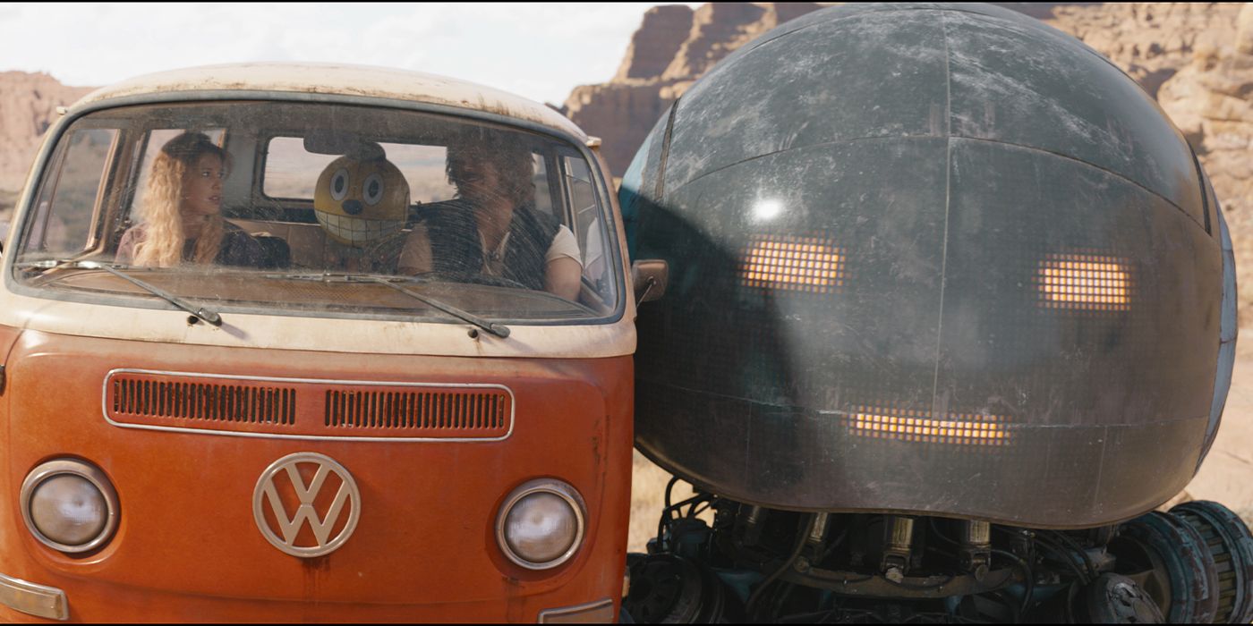 A giant robot holding up a Volkswagen van with Chris Pratt and Millie Bobby Brown inside