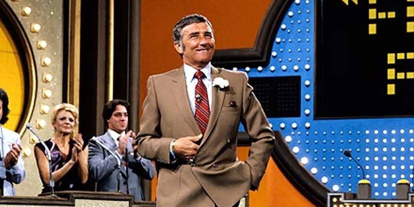 Richard Dawson smiling, hand in pocket with a family clapping behind him in Family Feud.