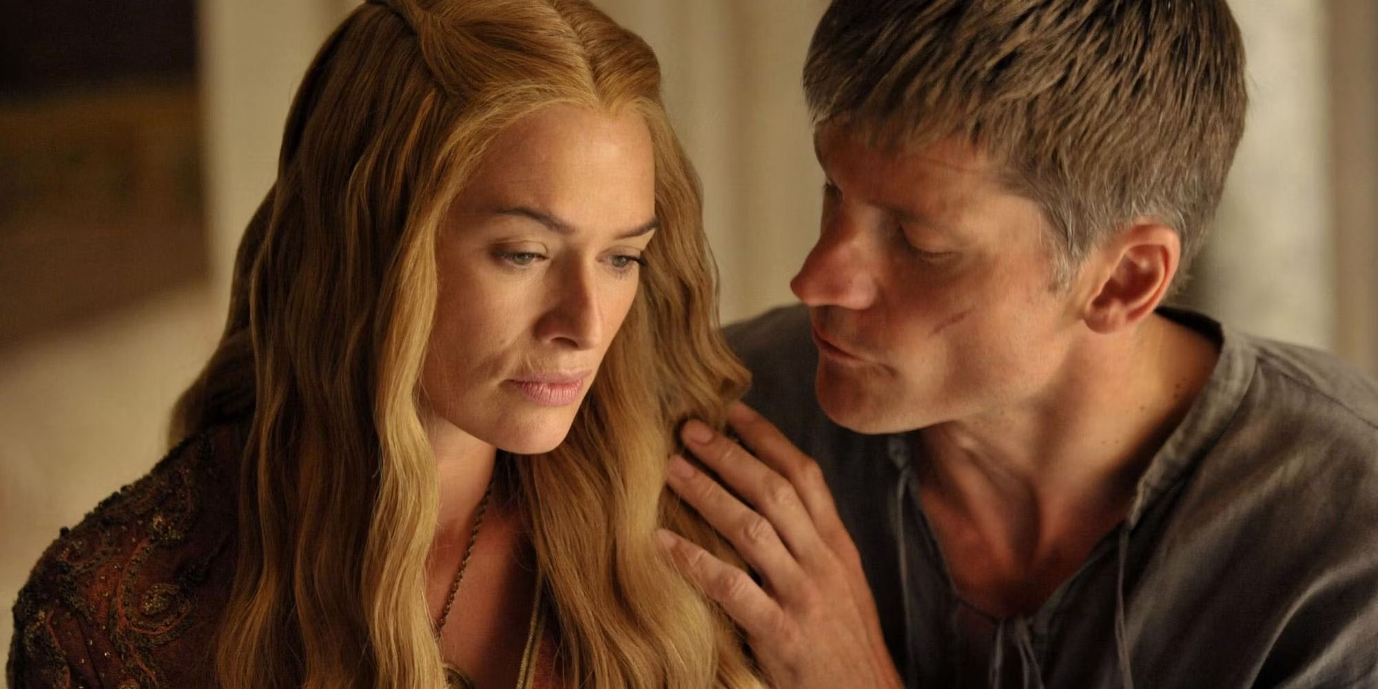 Lena Headey and Nikolaj Coster-Waldau sit close to each other and look serious in Game of Thrones.