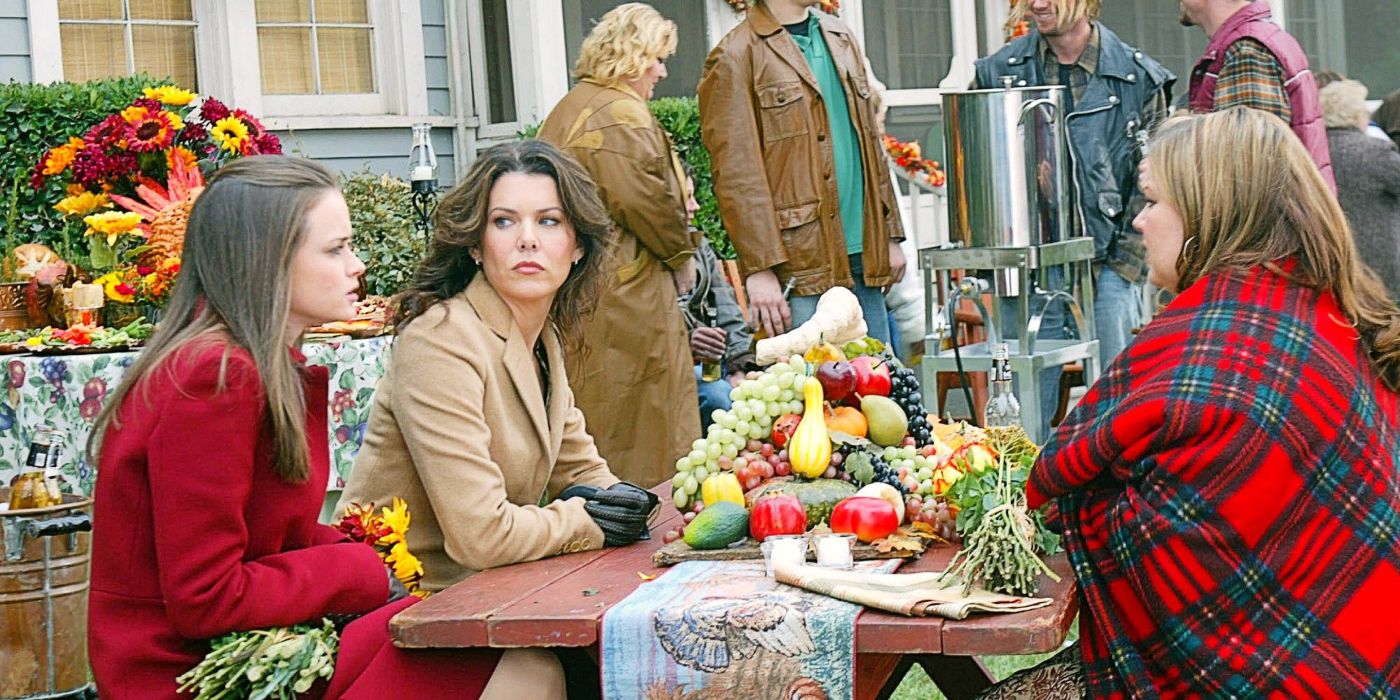 Rory, Lorelai, and Sookie sitting down together for Thanksgiving dinner in Gilmore Girls