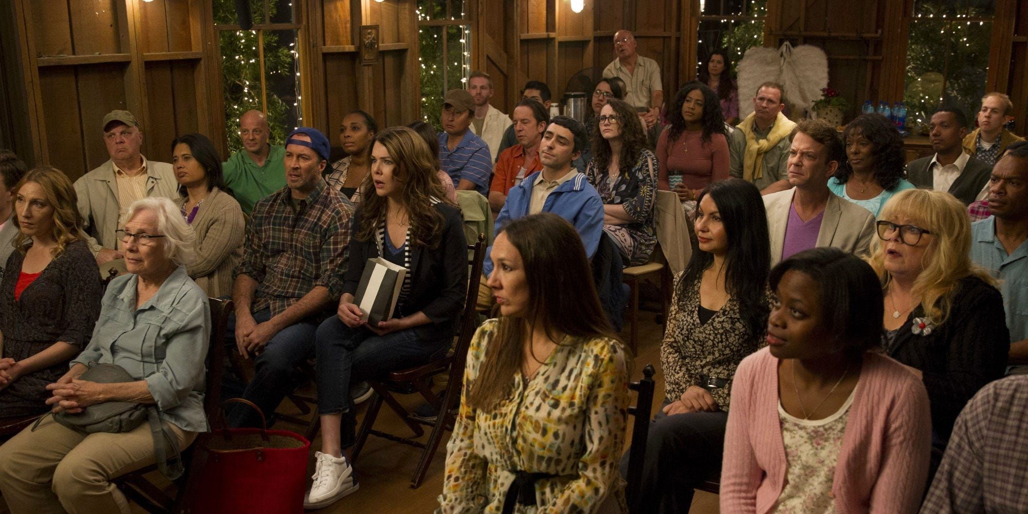 The townspeople of Stars Hollow sit in a town hall meeting in Gilmore Girls.