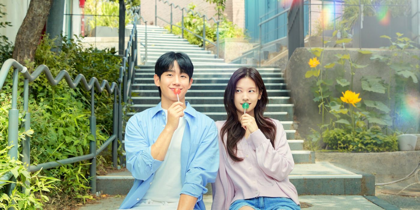 Jung Hae-in, as Seung-Hyo, and Jung So-min, as Seok-ryu from love next door eating lollipops and smiling forward on the steps.