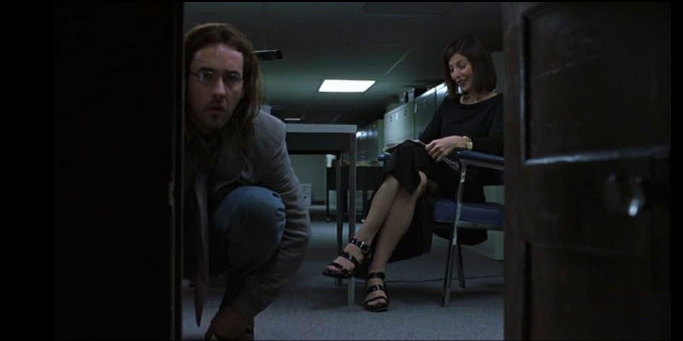 John Cusack faces the camera as he kneels in front of a small door while Catherine Keener sits on a chair behind him in &lsquo;Being John Malkovich&rsquo;