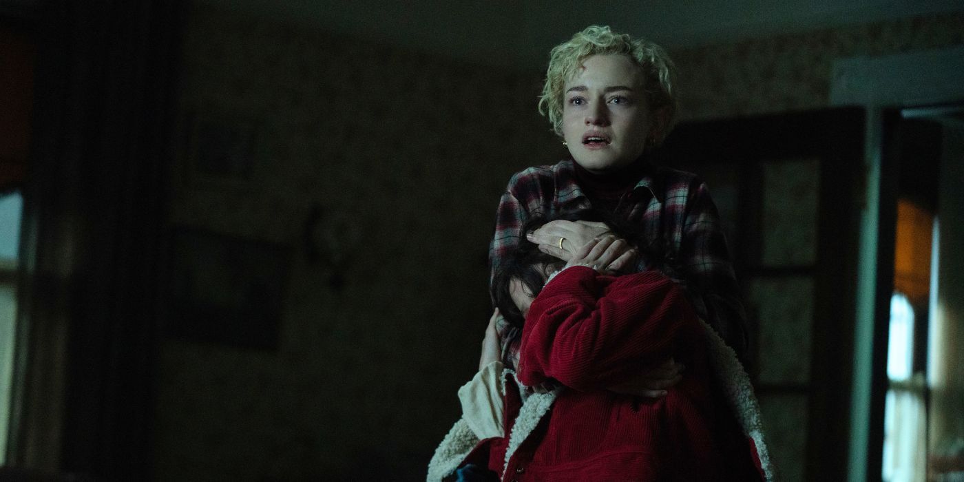 Julia Garner as Charlotte clutching her daughter in fear in Wolf Man.