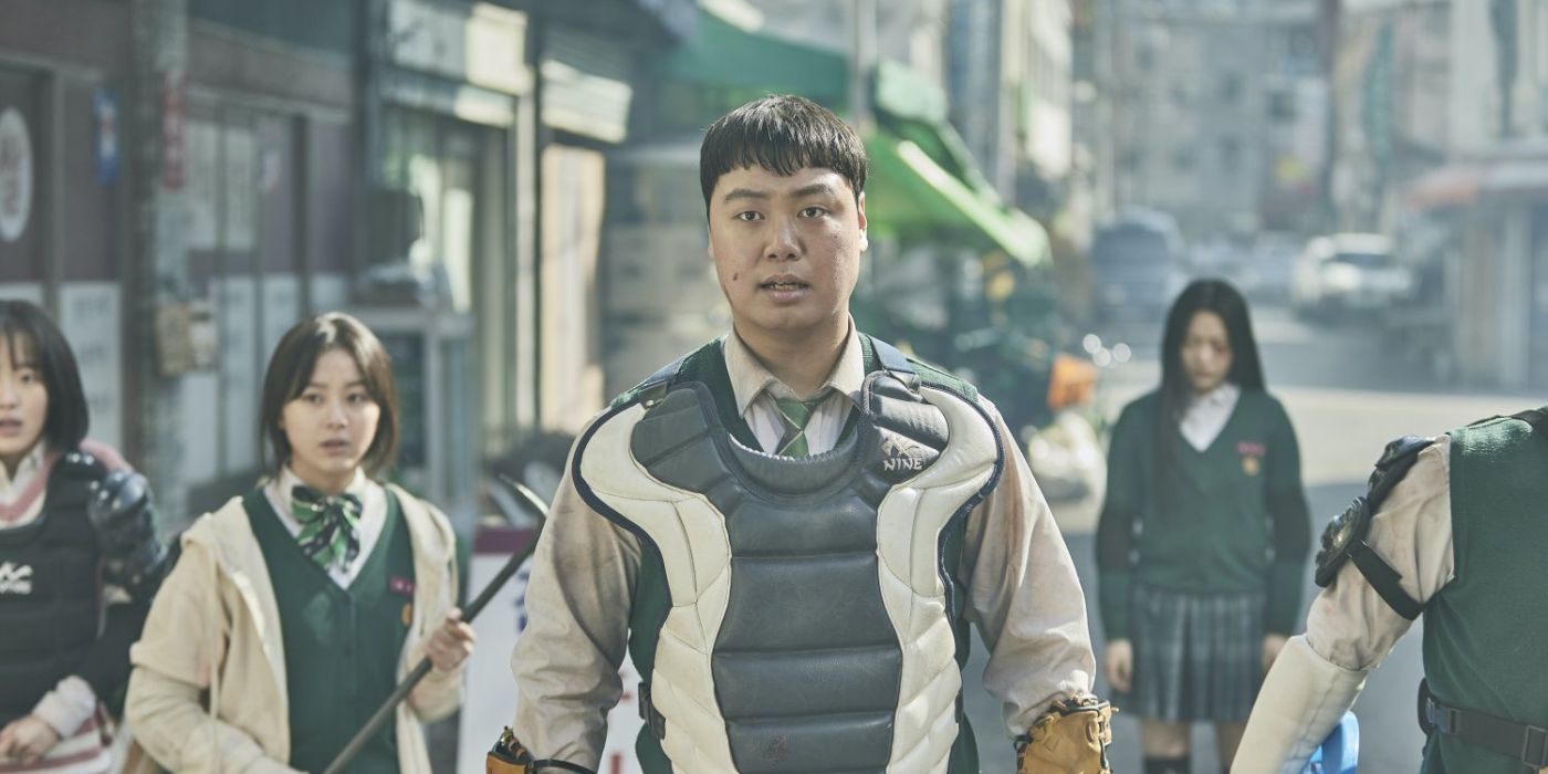 A group of student apocalypse survivors stand with makeshift weapons and armor in the street