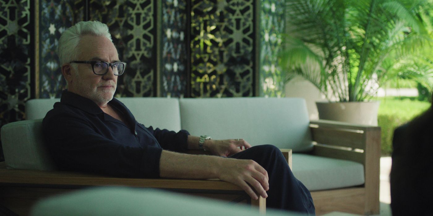 Bradley Whitford wears a blue button-up shirt and sits on a white couch in 'The Madness'