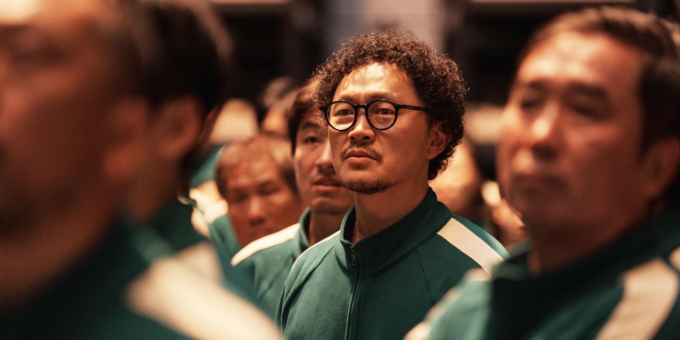 in his green uniform and glasses Yang Dong-geun stands at attention in 'Squid Game' S2