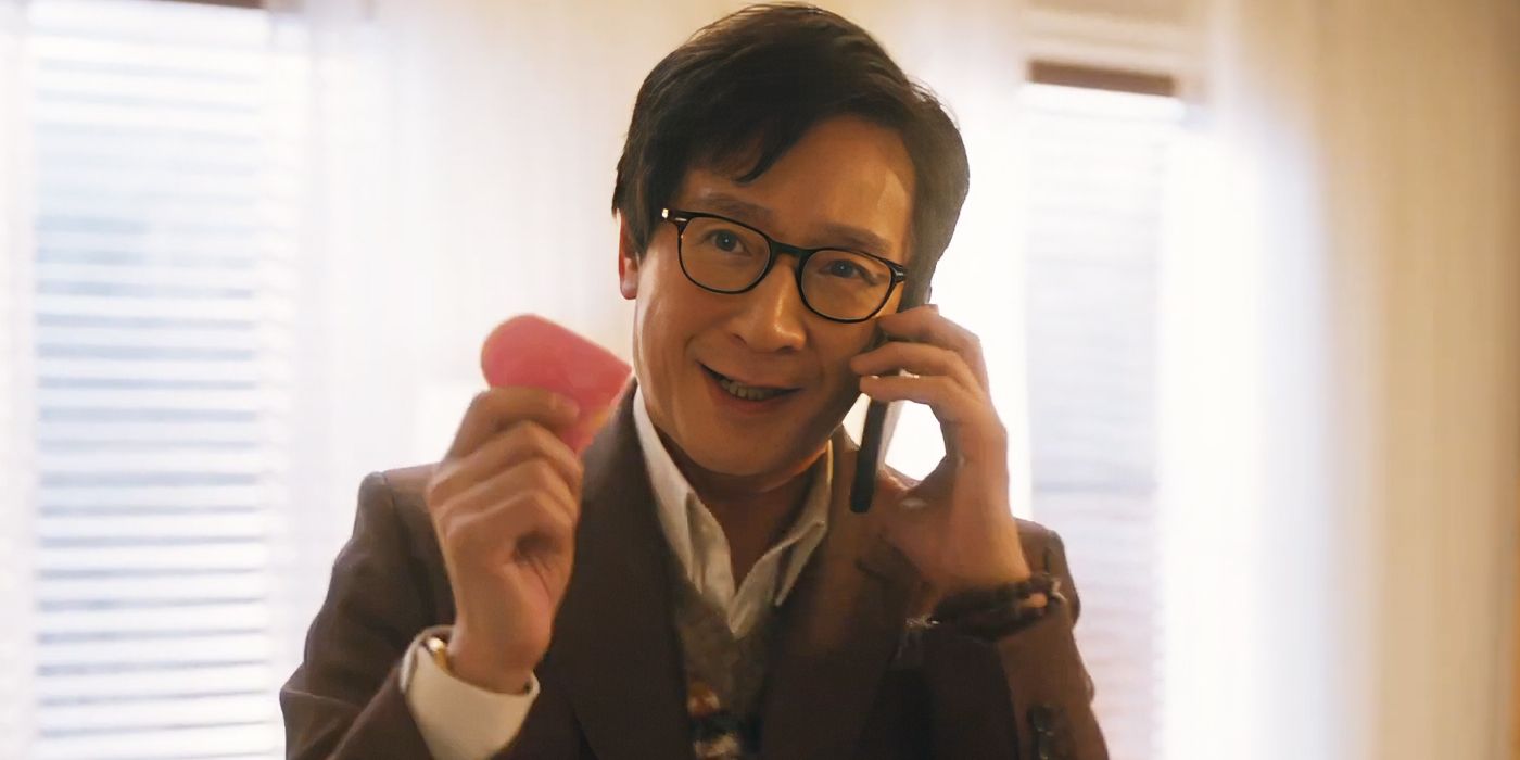 Ke Huy Quan as Marvin Gable on his cell phone with a smile in Love Hurts