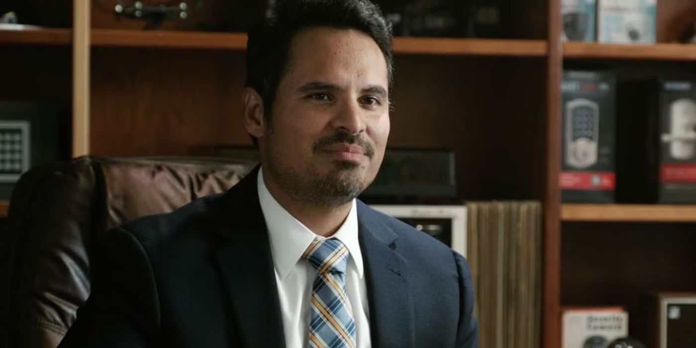 Luis wears a suit and tie and sits in an office chair in Ant-Man and The Wasp.