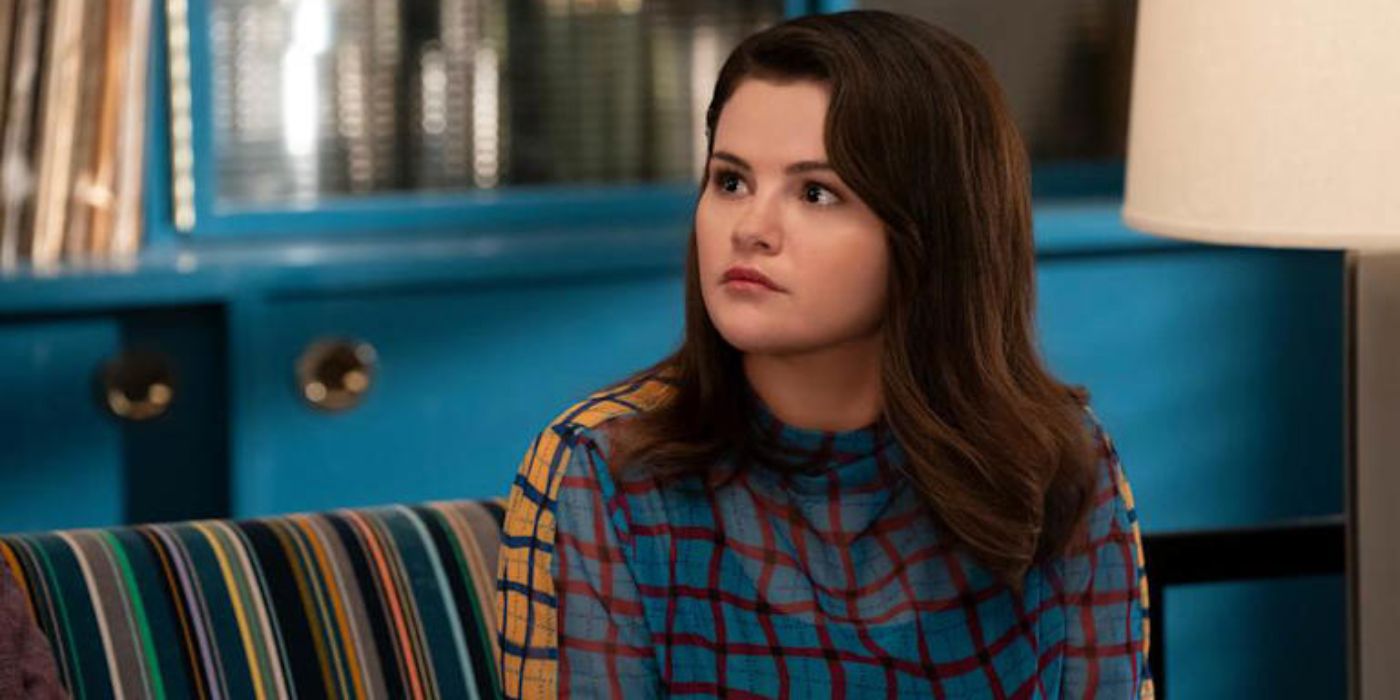 Selena Gomez as Mabel sitting on a couch and looking to the side in Only Murders in the Building. 