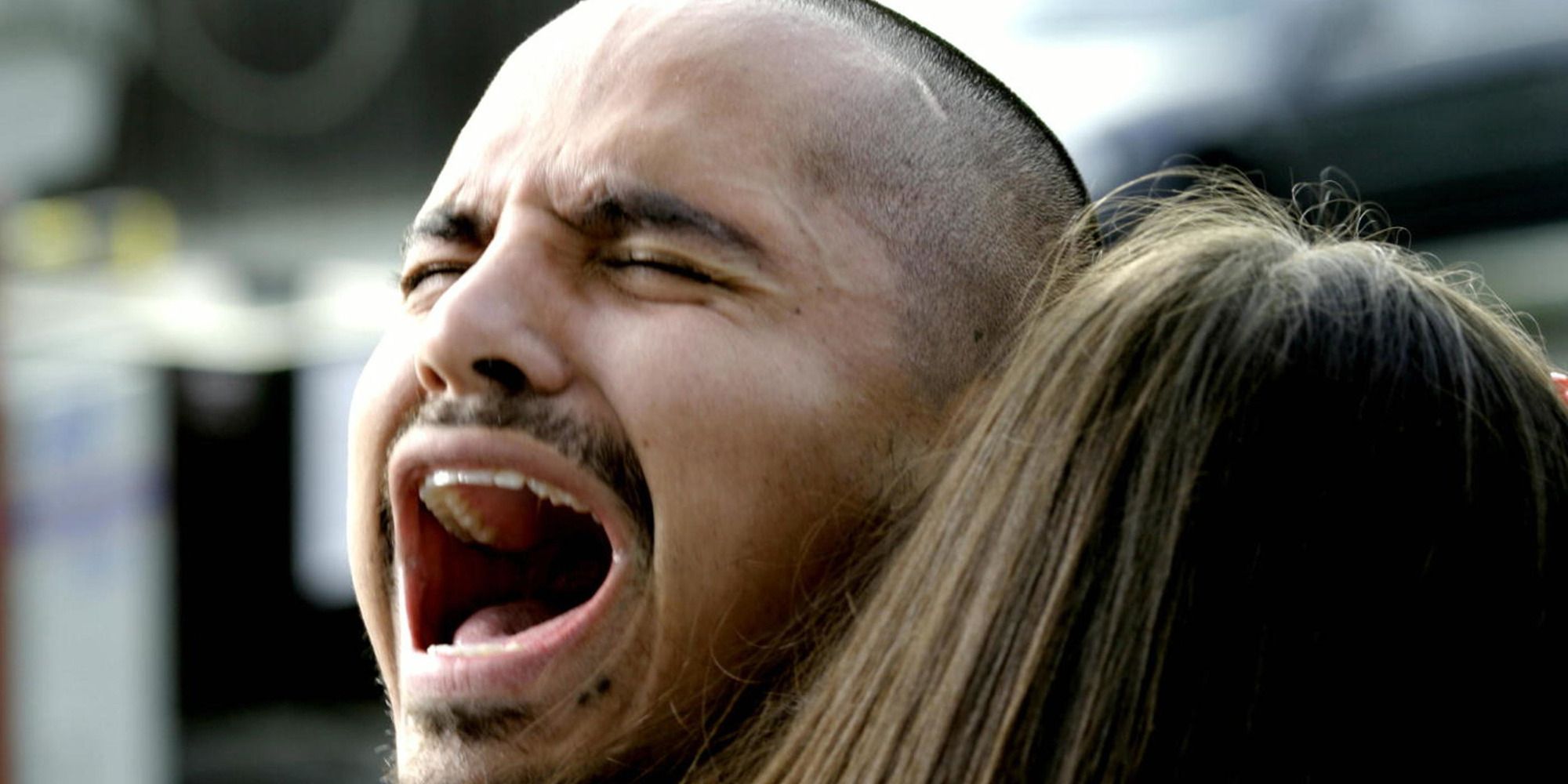 Michael Peña screaming while a woman holds him in Crash.