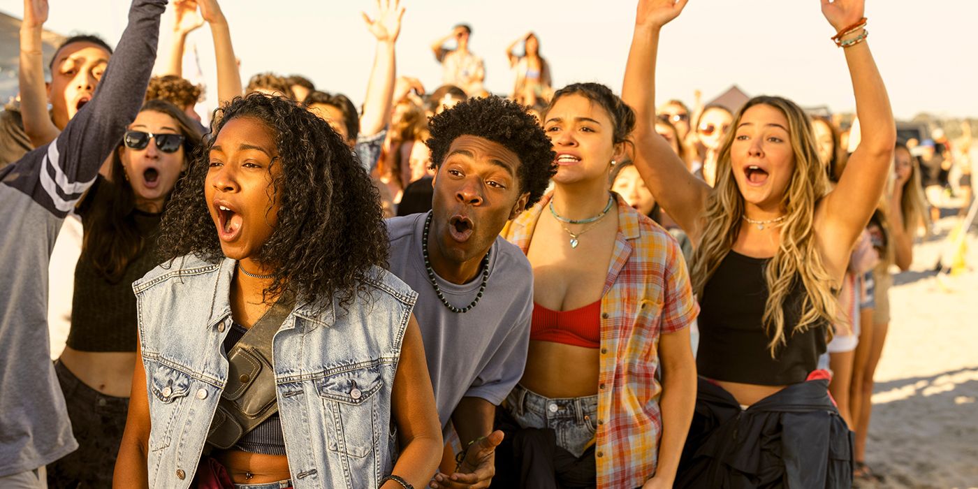 Carlacia Grant as Cleo, Jonathan Daviss as Pope, Madison Bailey as Kiara, and Madelyn Cline as Sarah all cheering on their friends outside during a race in Outer Banks Season 4 Part 1