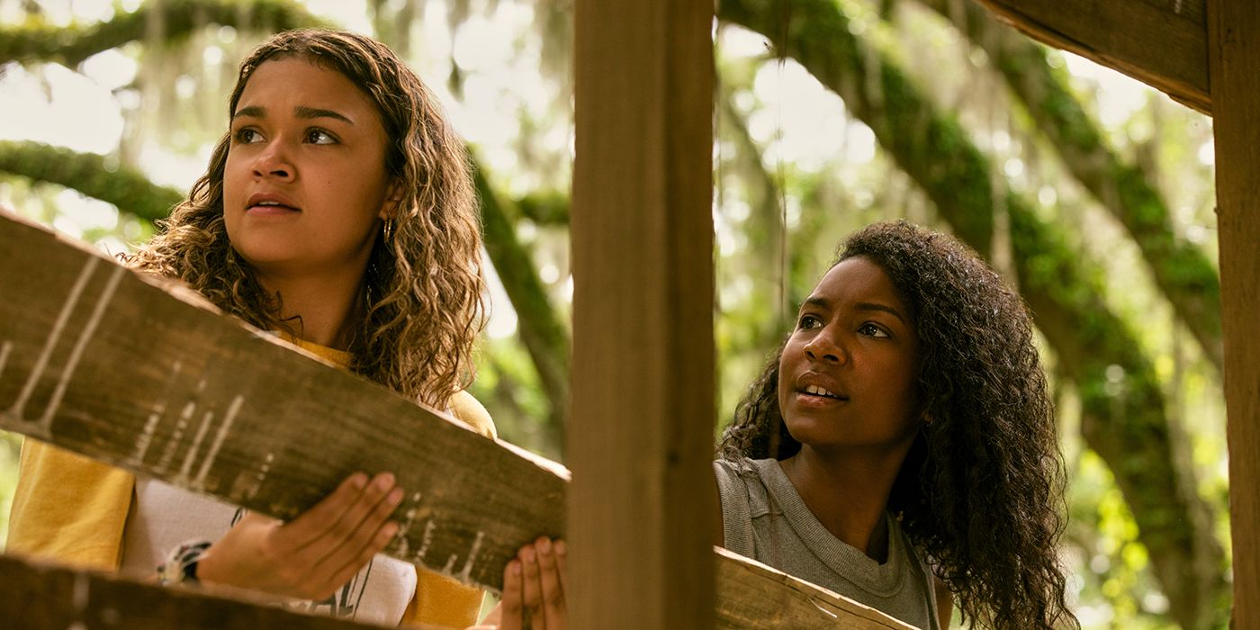 Kiara and Cleo holding a plank of wood and helping to build a house together in Outer Banks Season 4 Part 1