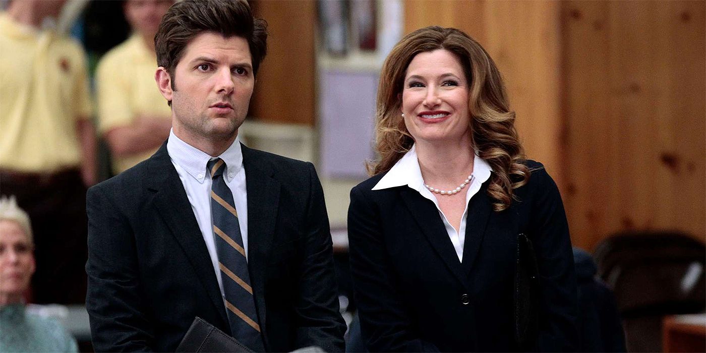 Ben Wyatt frowning and looking into middle distance while Jennifer Barkley smiles happily standing next to him