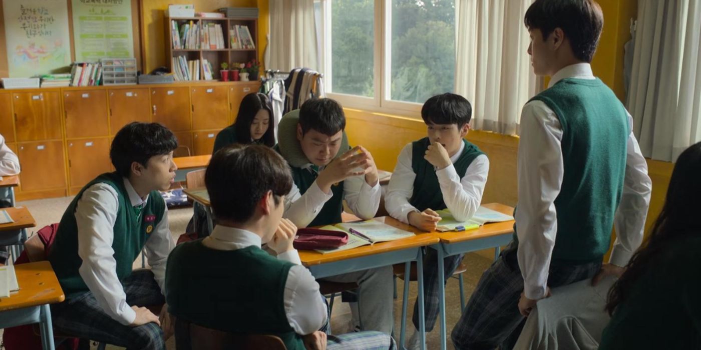 A group of teen students huddle around a desk All of Us Are Dead