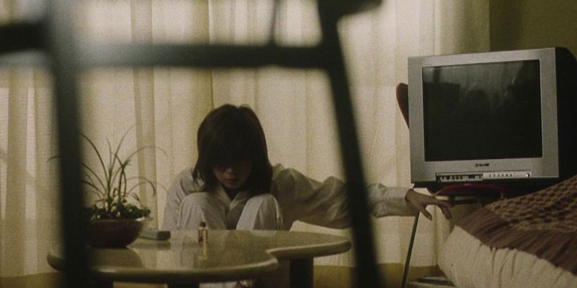 Kurume Arisake as Junko Sadako sitting next to a TV in 'Pulse' (2001)