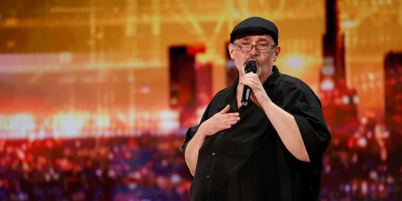 Contestant Richard Goodall sings onstage with a cityscape background on America's Got Talent.